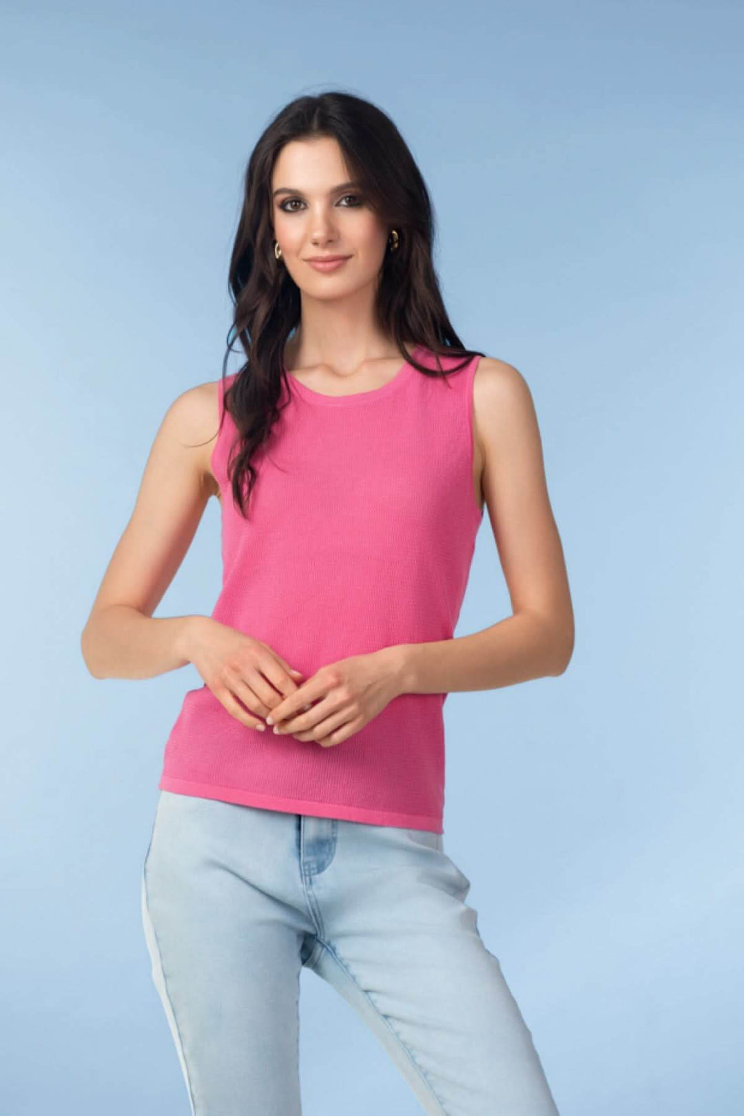 Femme portant une camisole en maille texturée rose avec un jean, mettant en avant un style épuré et moderne.