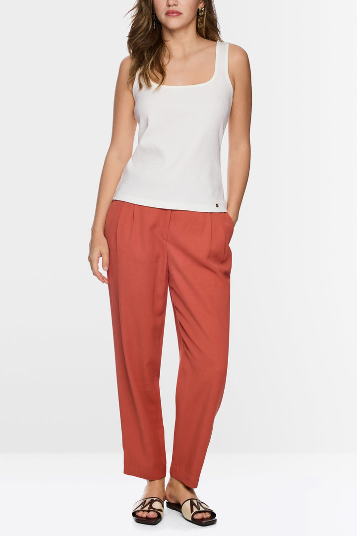 Camisole à encolure carrée blanche portée avec un pantalon rouge, offre un style moderne et minimaliste pour un look tendance.