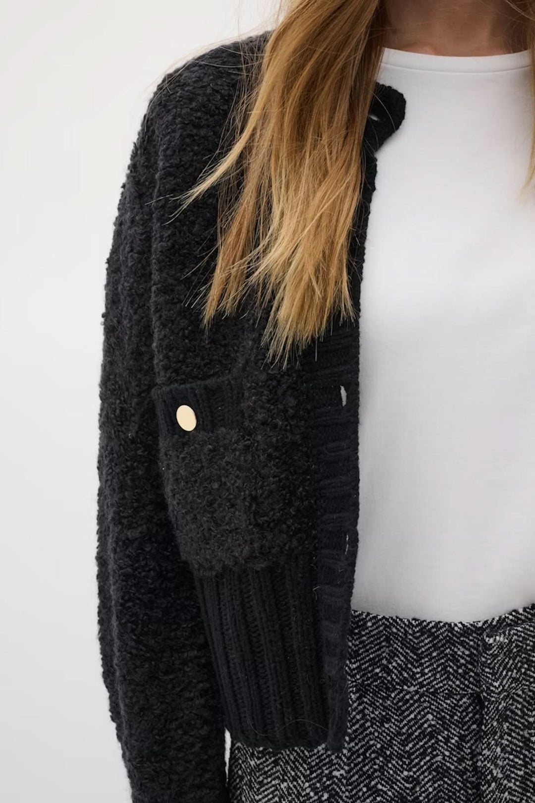 Cardigan Guo à coupe courte avec boutons dorés et maille texturée, porté avec un pantalon chic. Sophistiqué et moderne.