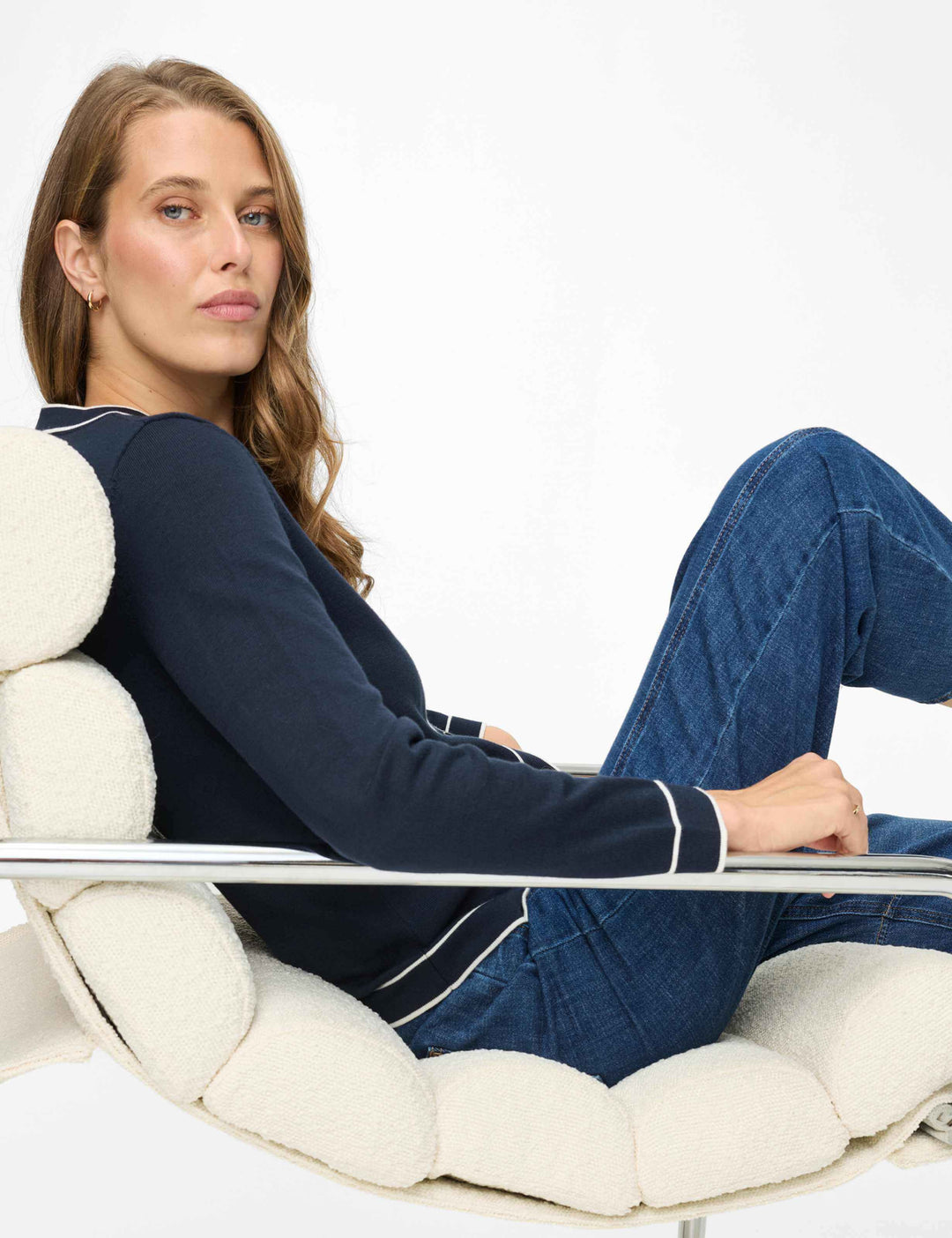Femme portant un Cardigan boutonné à col contrasté ANN, assise confortablement sur une chaise moderne avec un denim.