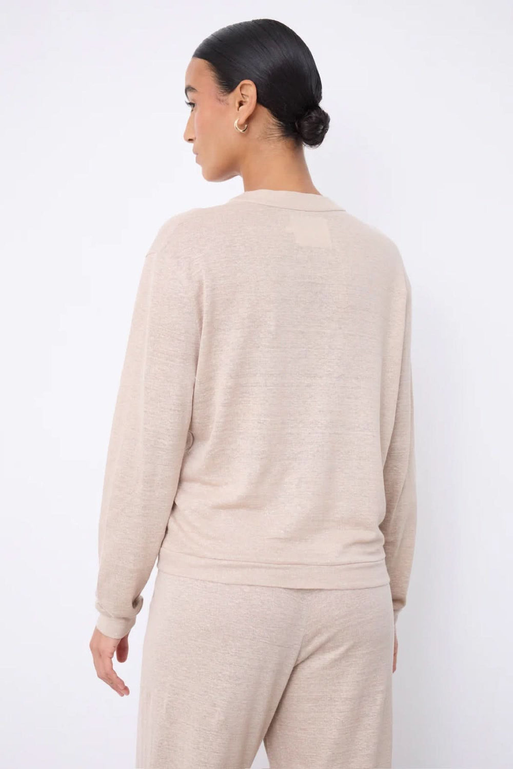 Vue arrière d'un cardigan col v boutonné léger en matière douce, porté par un modèle féminin.
