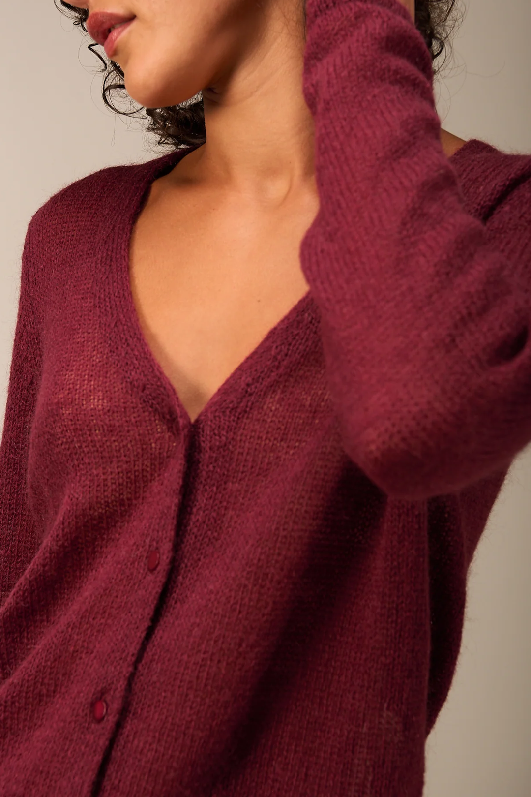 Femme portant un cardigan coupe droite encolure en V, couleur bordeaux avec boutons, style minimaliste et élégant.