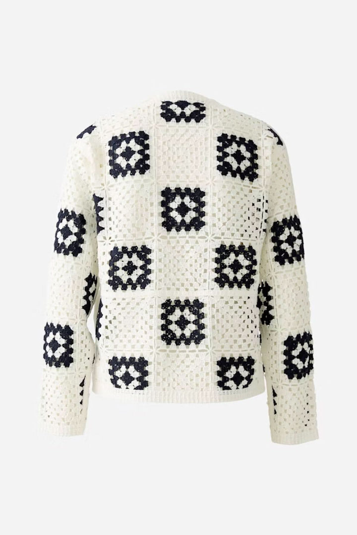 Cardigan en crochet blanc avec motifs géométriques marines, parfait pour un look bohème et décontracté.