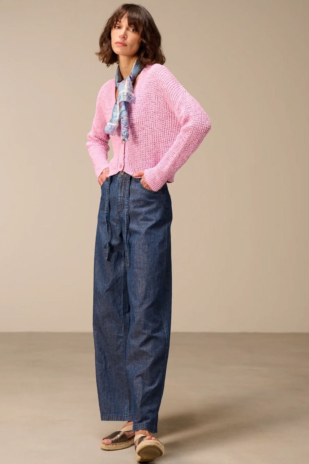 Femme portant un Cardigan en maille texturée à col en V rose avec un jean large.