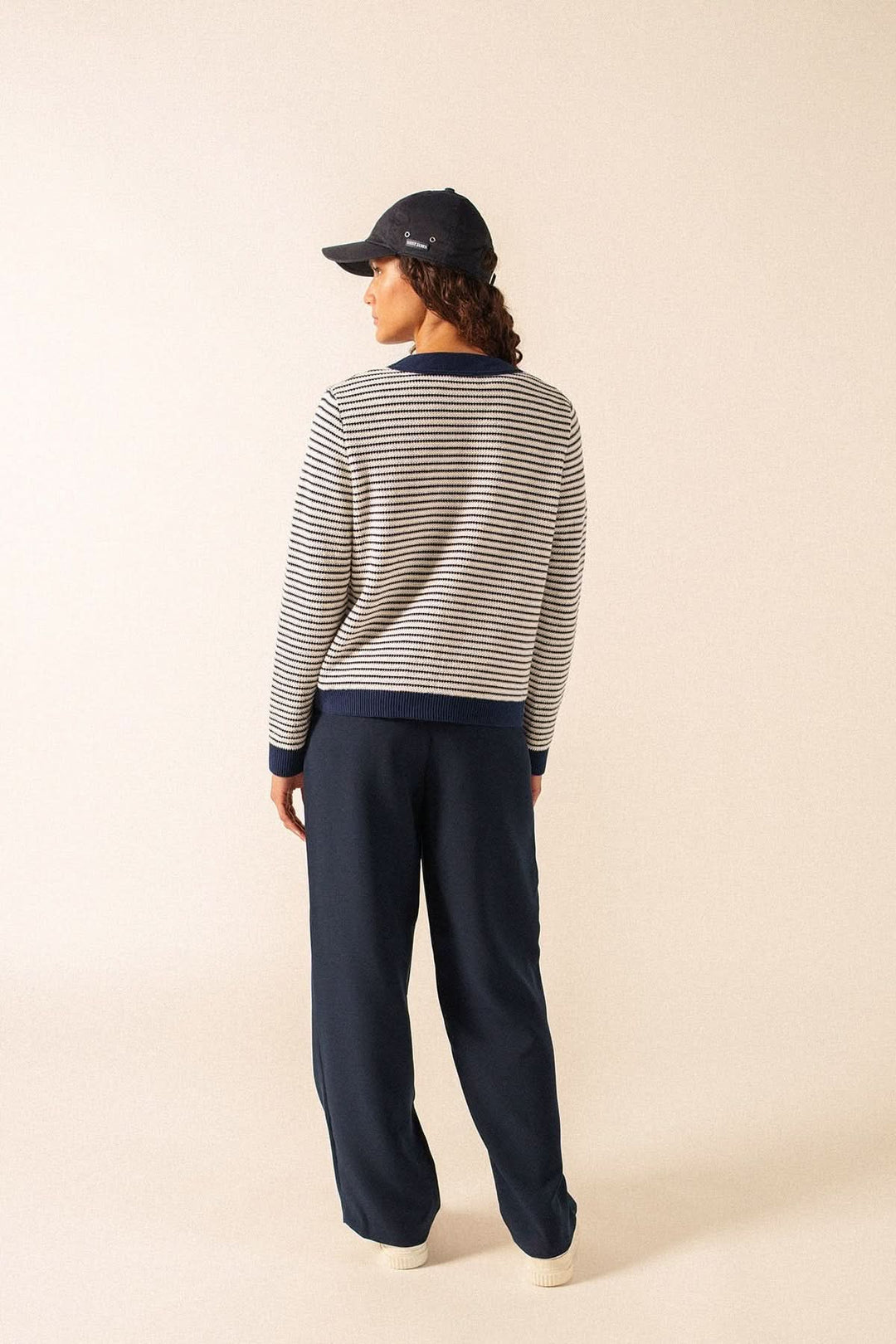Cardigan rayé style marin ISTRES porté par une femme de dos, look décontracté avec pantalon bleu marine et casquette.