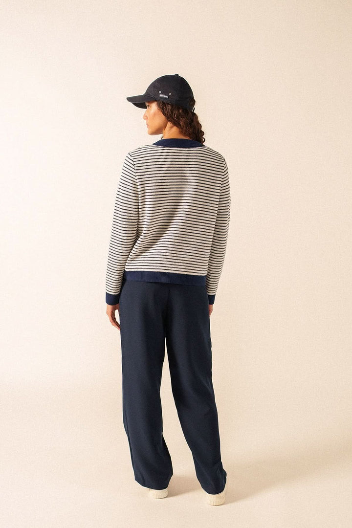 Cardigan rayé style marin ISTRES porté par une femme de dos, look décontracté avec pantalon bleu marine et casquette.