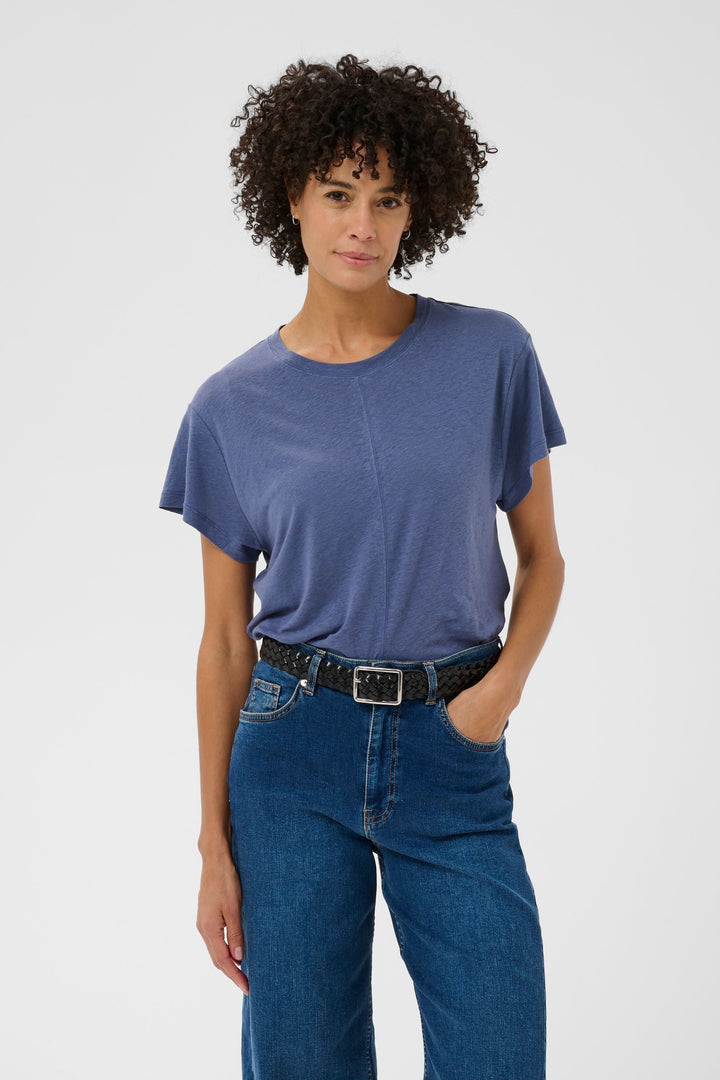 Femme portant le Chandail Anemona bleu avec coupe ample et couture centrale, idéal avec un jean pour un style polyvalent et moderne.