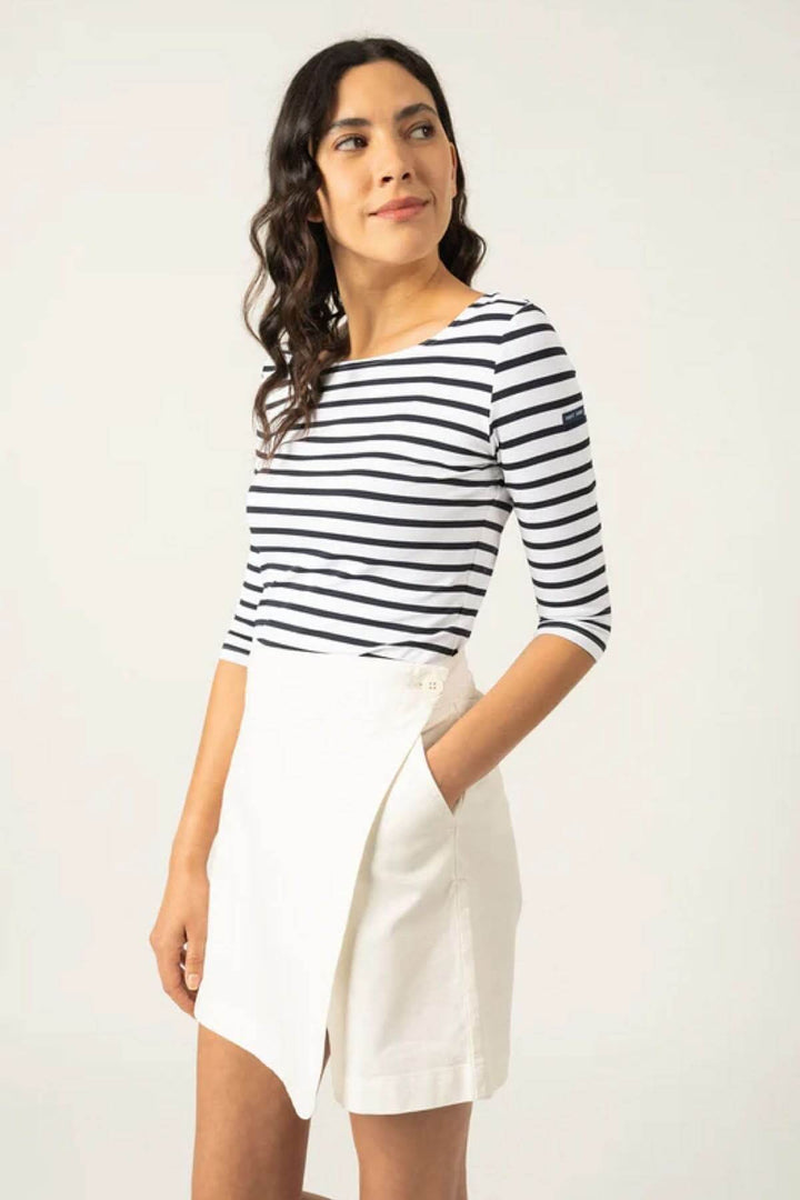 Femme portant un chandail rayé à manches 3/4 avec une jupe blanche, illustrant l'élégance décontractée du modèle Garde-côte III R.