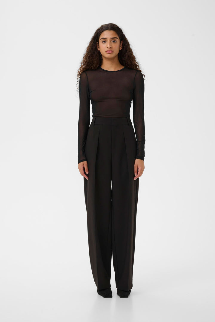 Modèle portant le Chandail Kaia en tulle transparent à manches longues, style moderne et ajusté pour une allure sophistiquée et contemporaine.