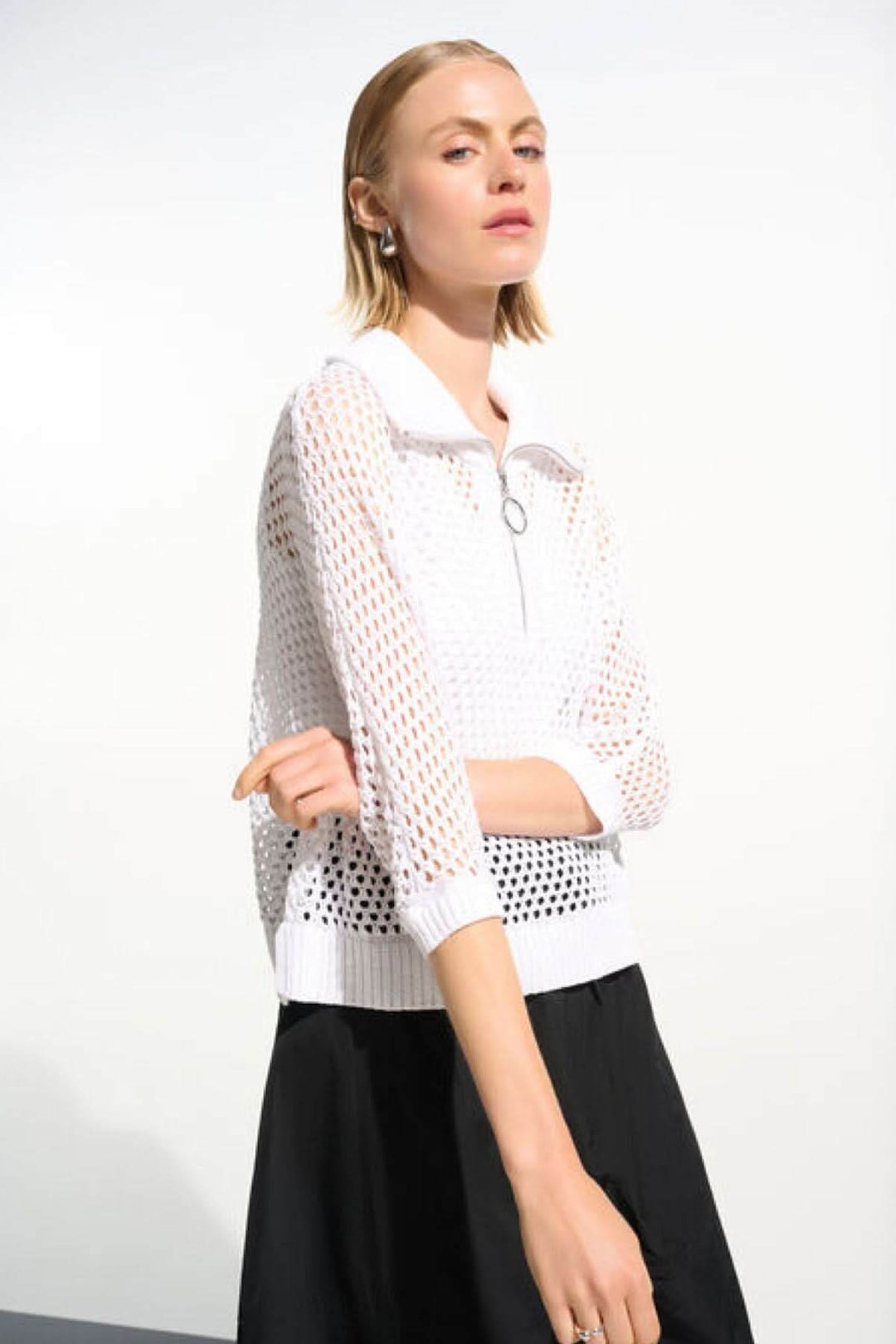 Femme portant un chandail ajouré à col zippé avec manches trois-quarts, idéal pour un look moderne et léger.