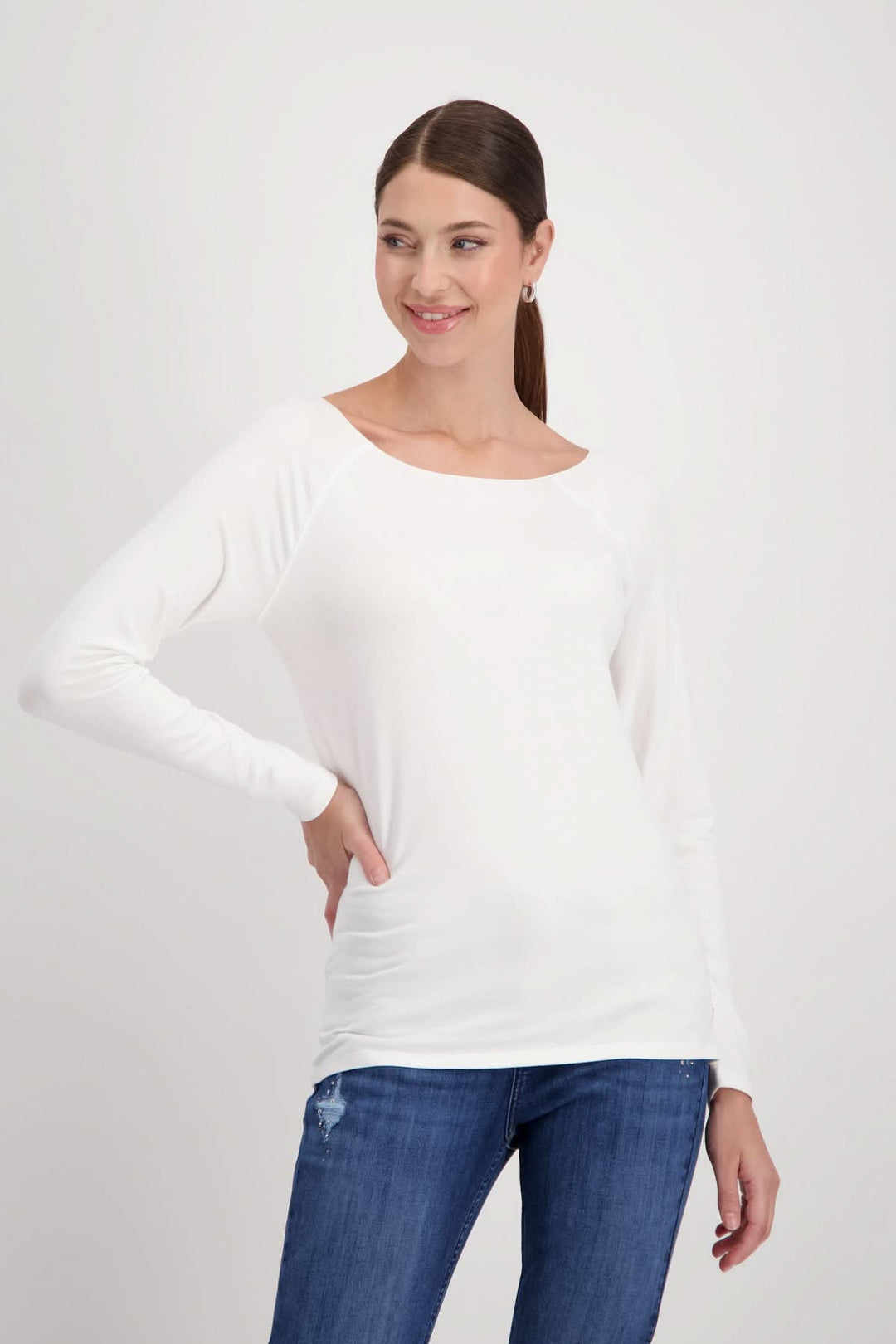 Chandail basique blanc en tissu doux, à manches longues raglan, porté avec un pantalon en denim.
