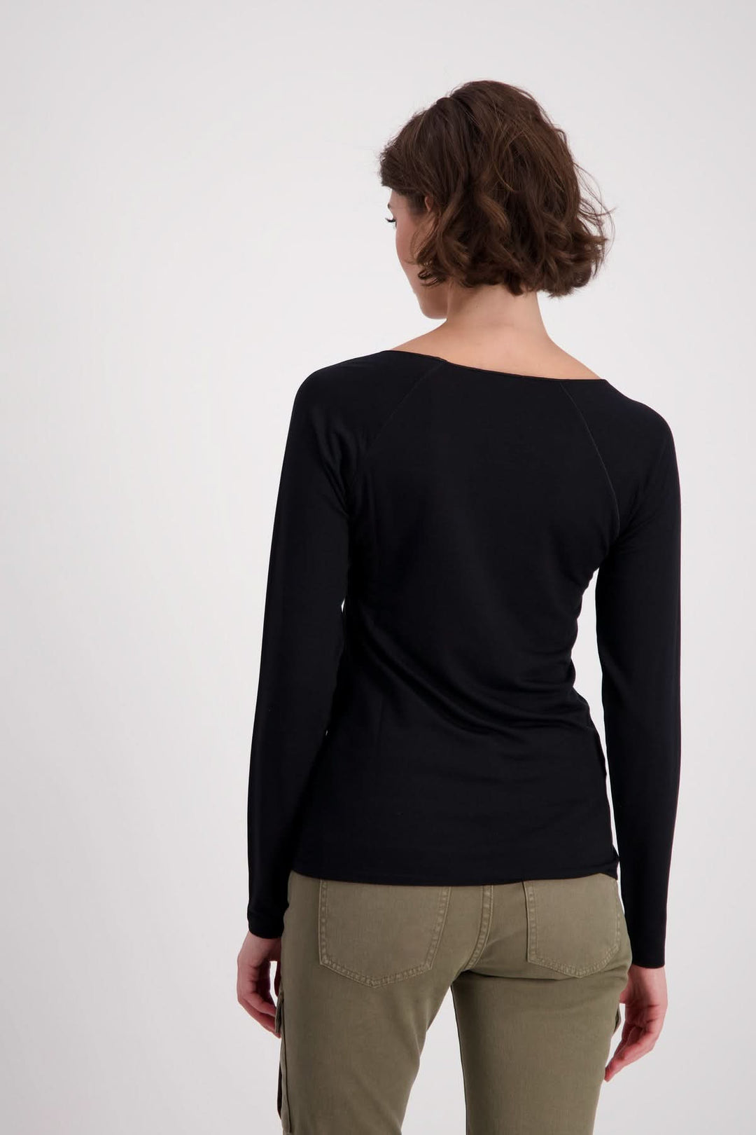 Femme vue de dos portant un chandail basique noir aux manches longues raglan et coupe légèrement cintrée.