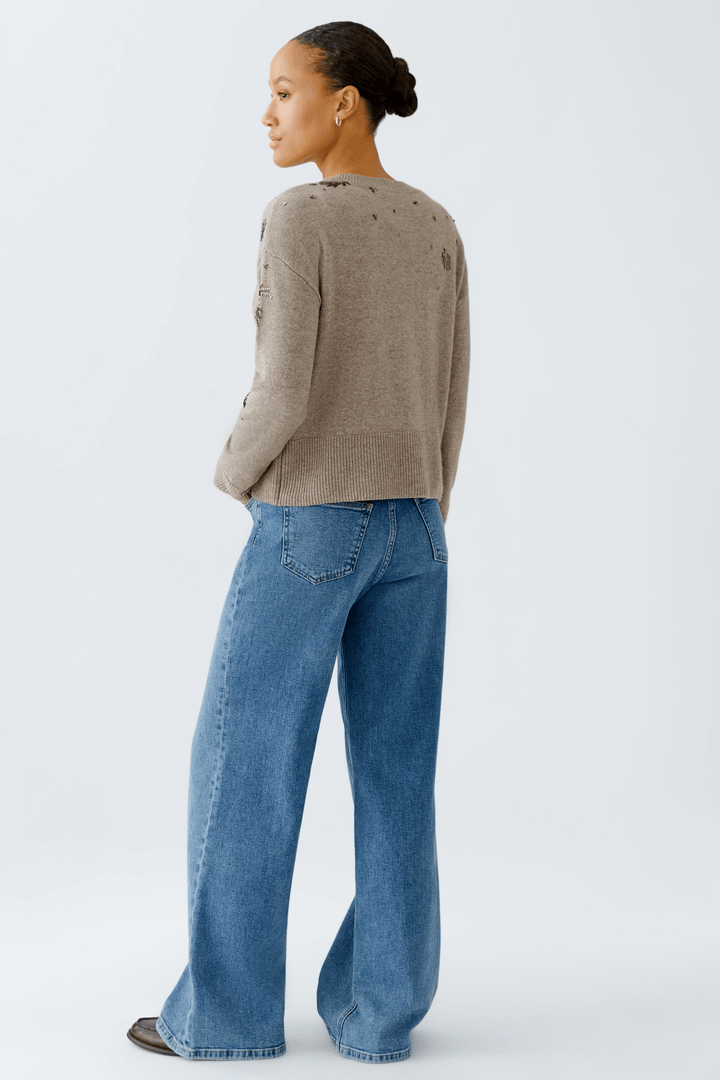 Femme portant un chandail broderies avec jean, vue de dos, mettant en valeur le tricot doux et les broderies élégantes.