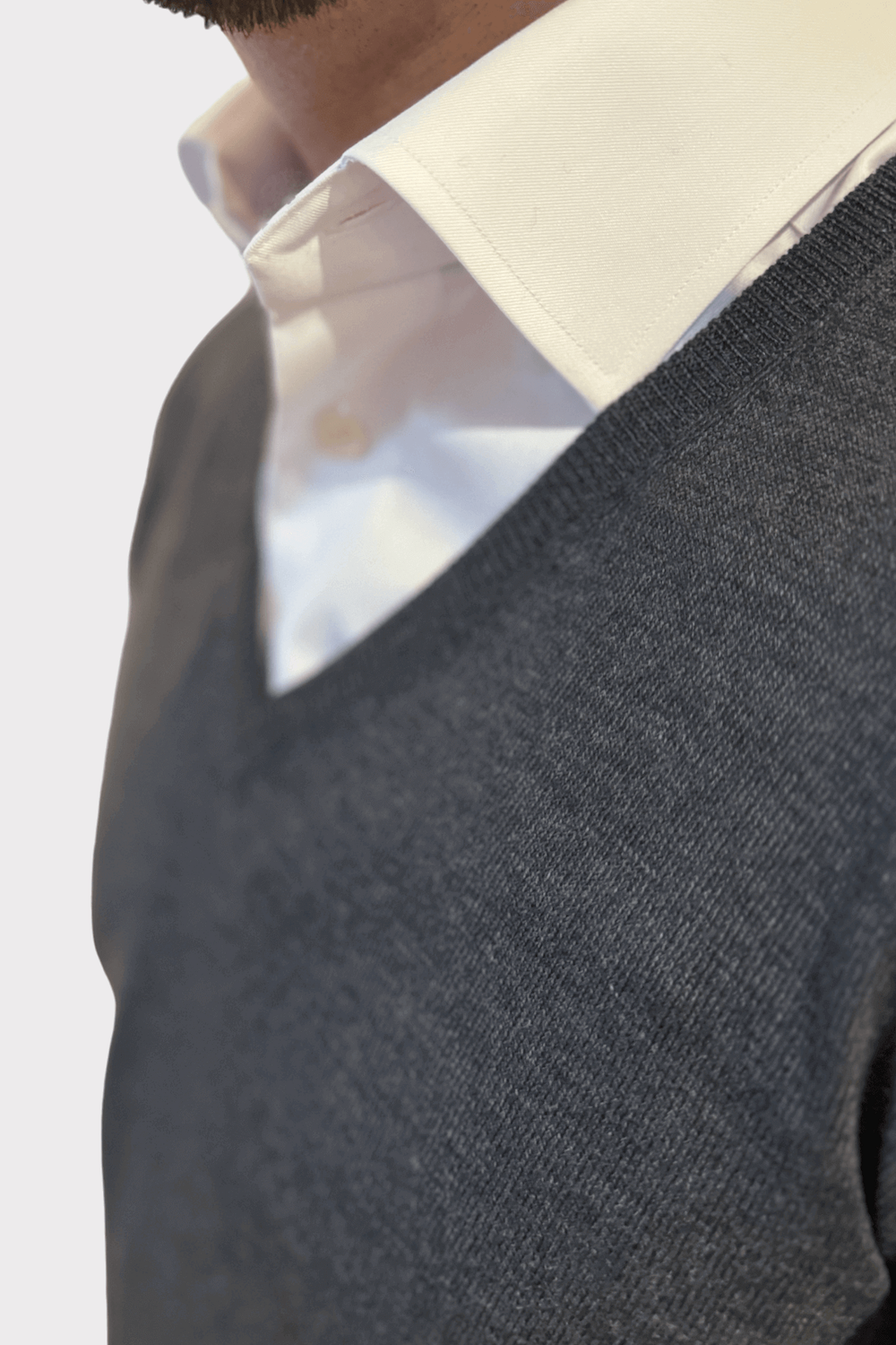 Pull en V en laine gris porté sur une chemise blanche, élégant et confortable, idéal pour le style quotidien.