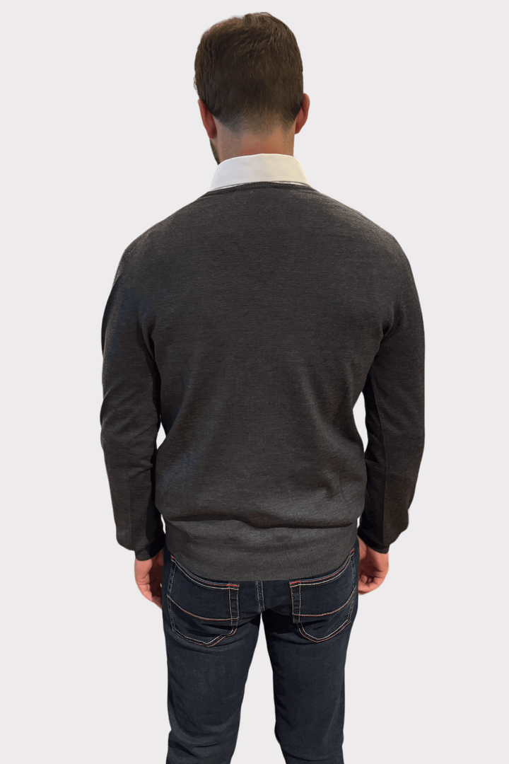 Homme vu de dos portant un chandail col en V en laine, taille ajustée et élégant, avec une chemise blanche en dessous.