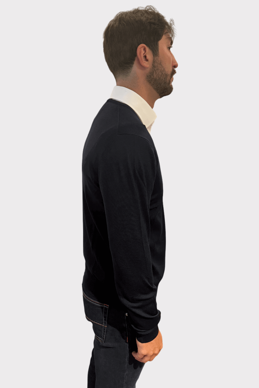 Chandail col en V noir en laine porté par un homme avec chemise blanche, vue de profil.