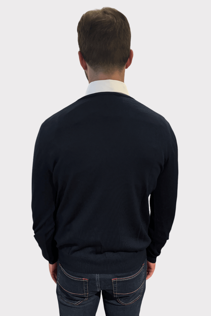 Homme portant un chandail col en V de laine, vu de dos, avec une chemise blanche dessous.