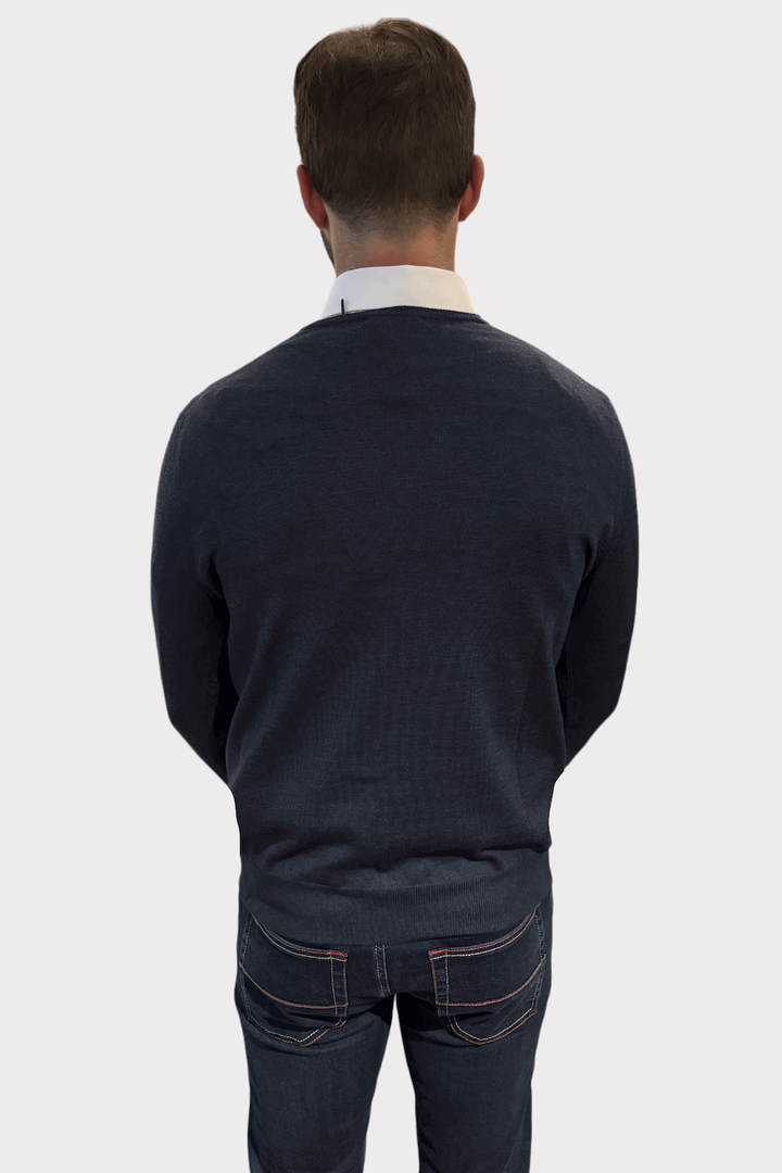 Homme portant un pull col en V en laine avec chemise blanche, vue arrière, style élégant et décontracté.