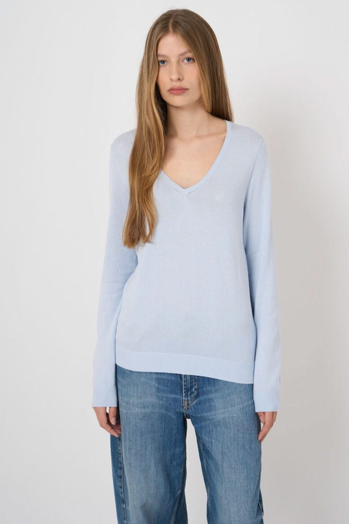 Chandail col en V manches longues en maille douce, modèle intemporel pour un style polyvalent, porté par une femme.