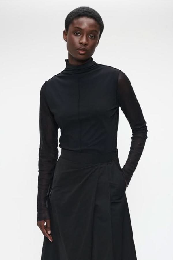 Chandail à col montant et manches transparentes minimaliste et élégant pour tenues de soirée ou looks professionnels chics.