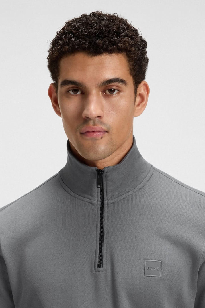 Homme portant un chandail à col montant zippé en coton Terry gris avec un écusson BOSS discret.