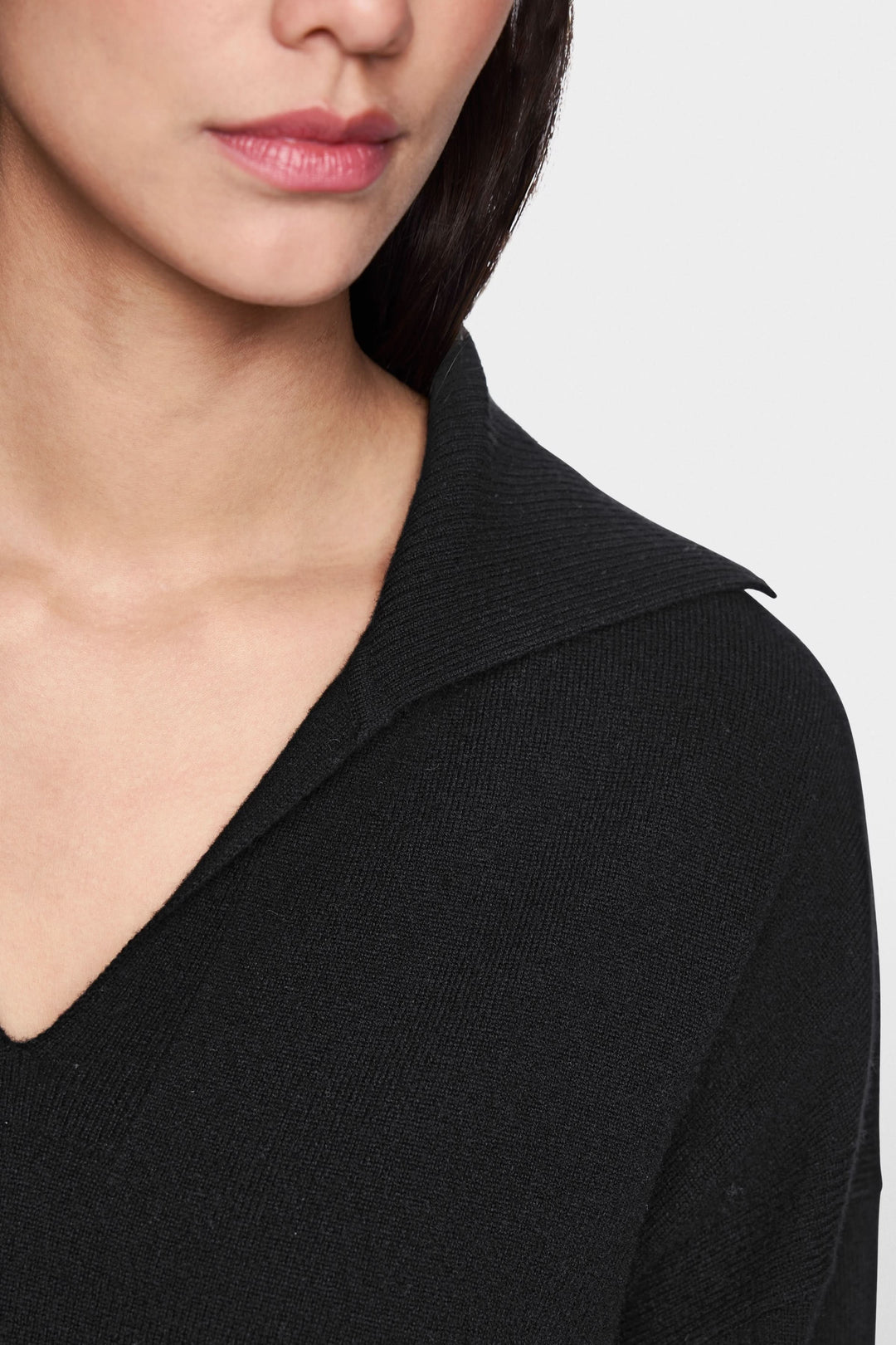 Femme portant un chandail col ouvert noir avec col polo élégant et chic.