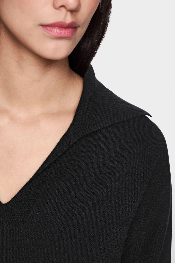 Femme portant un chandail col ouvert noir avec col polo élégant et chic.