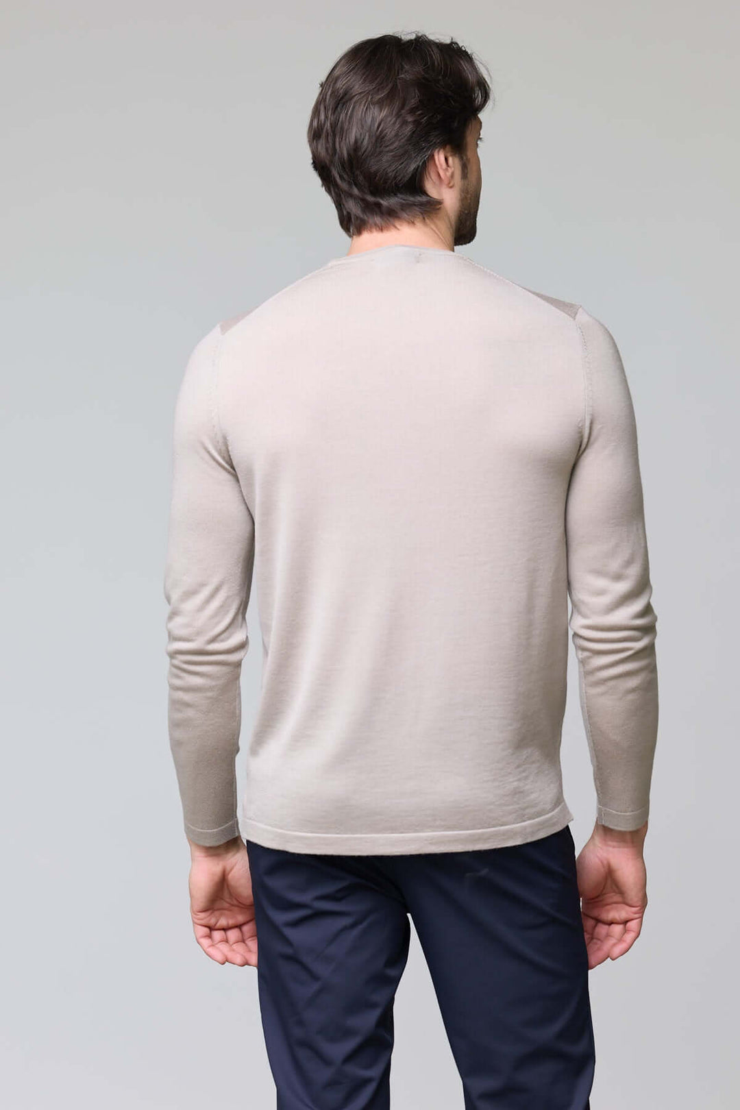 Homme portant un chandail col rond en tricot fin beige, vu de dos, illustrant la maille douce et ajustée du vêtement.