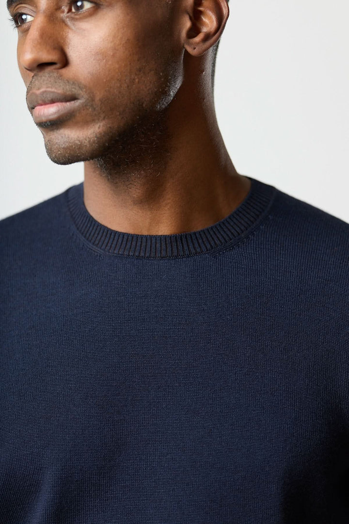 Homme portant un chandail col rond essentiel bleu avec finitions côtelées et un tombé net.