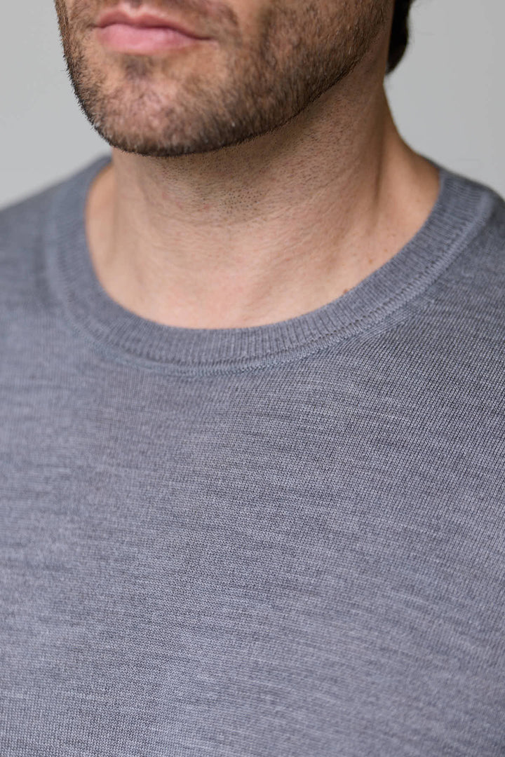 Homme portant un chandail col roulé en laine mérinos extra fine de couleur grise, montrant la douceur du tissu.