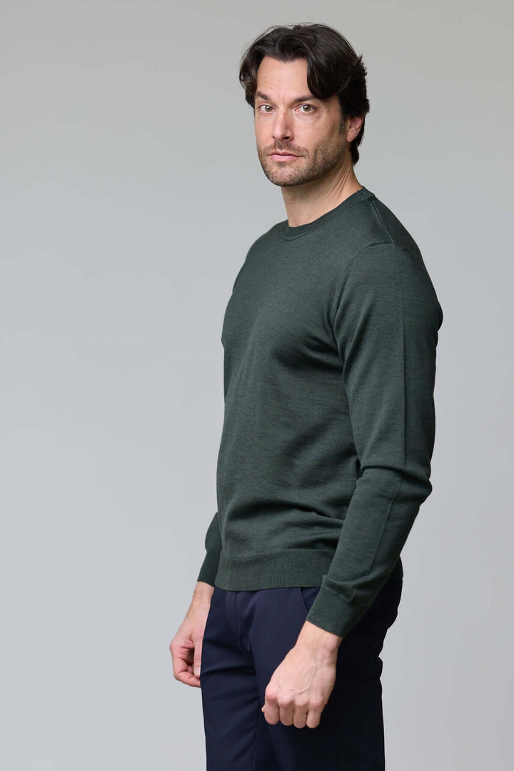 Homme portant un chandail col roulé en laine mérinos vert foncé, élégant et moderne.