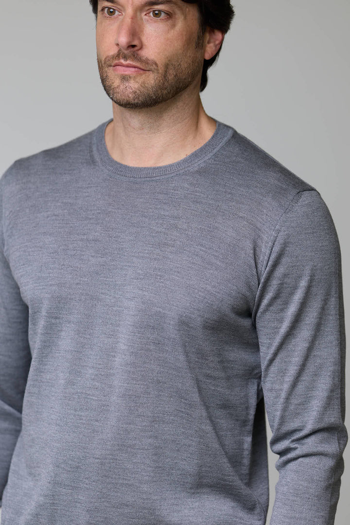 Homme portant un chandail col roulé en laine mérinos gris, manches longues, coupe ajustée, pour un look élégant et moderne.