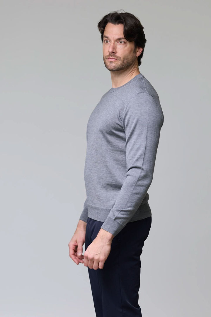 Homme portant un chandail col roulé en laine mérinos gris léger et moderne, parfait pour superposer ou porter seul pour un style élégant.