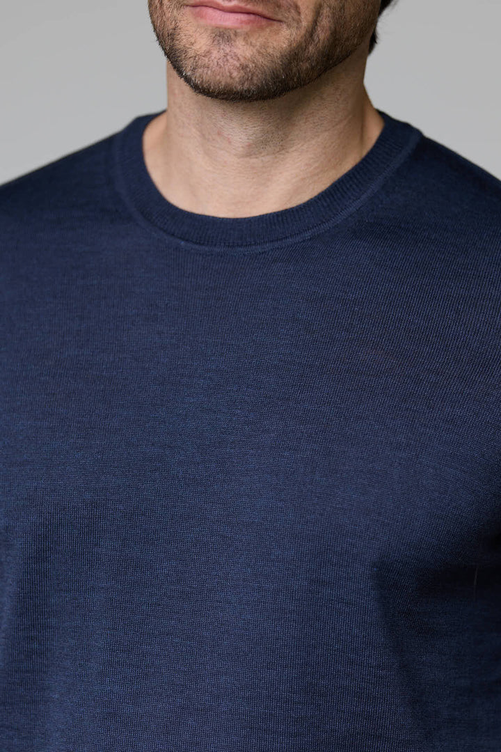 Homme portant un chandail bleu foncé à col rond en laine mérinos légère pour un confort optimal.