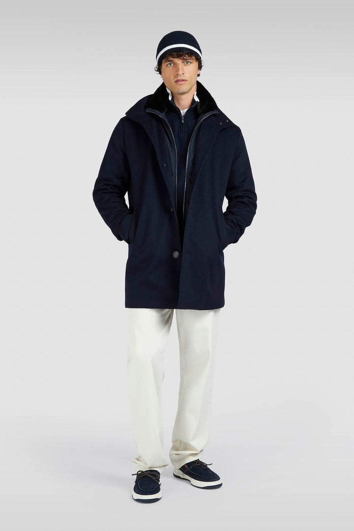 Homme portant un chandail à demi-fermeture avec capuche, pantalons beige et chaussures bleues, illustrant un style décontracté-chic.