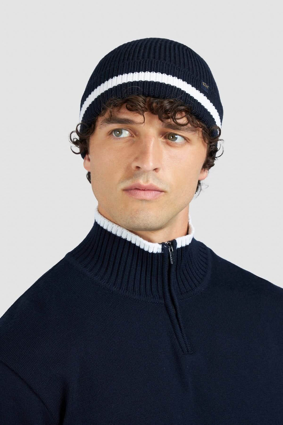 Chandail à demi-fermeture en bleu marine avec détails contrastants au col, porté par un mannequin portant un bonnet assorti.