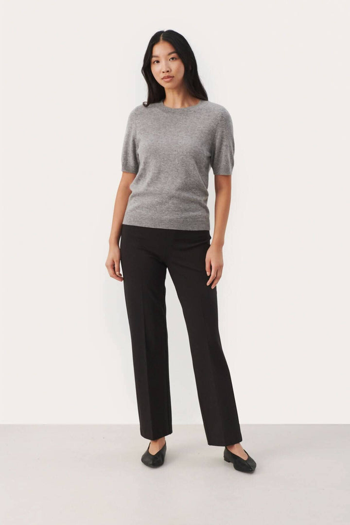 Chandail en cachemire gris à manches courtes, porté avec un pantalon noir élégant.