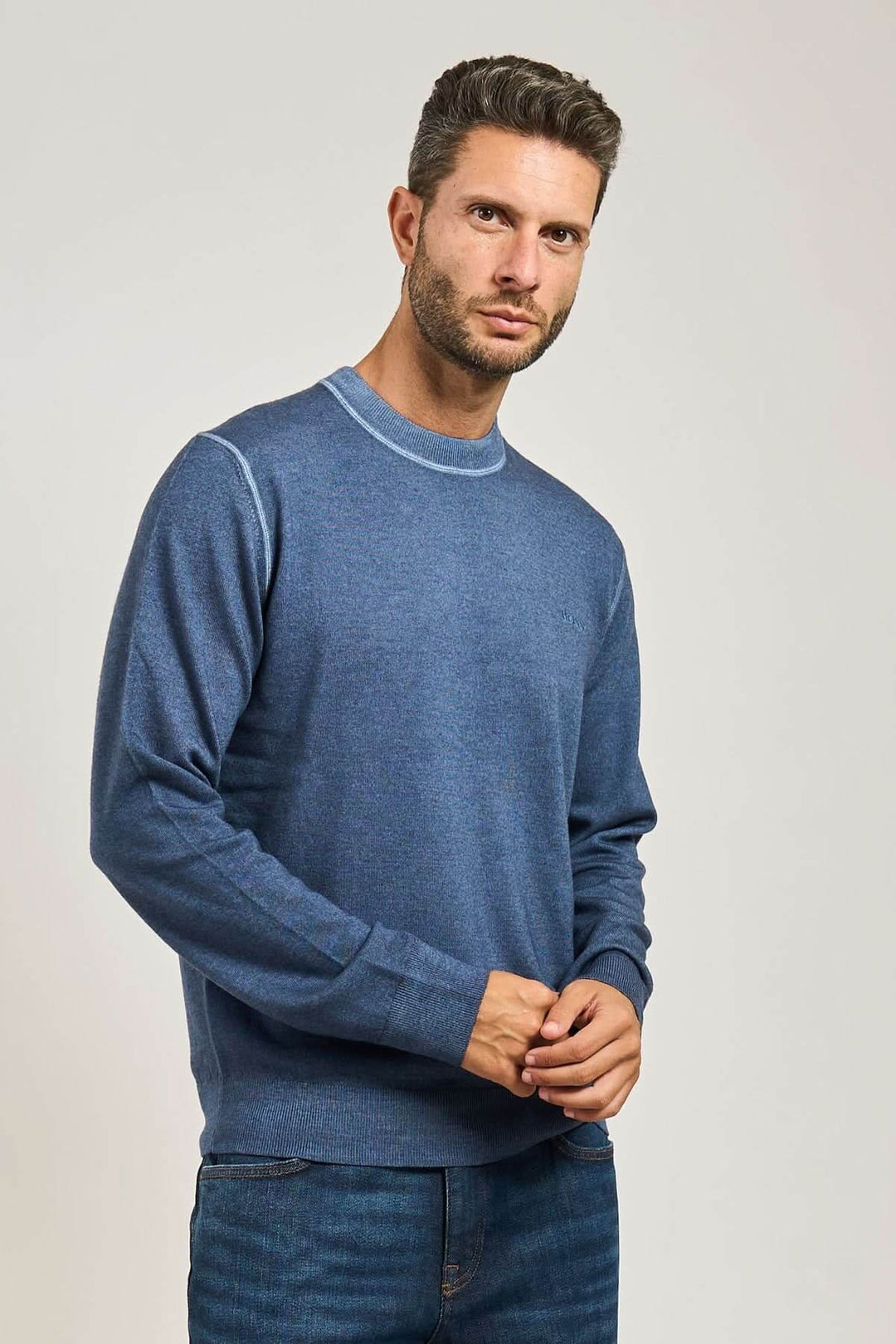 Homme portant un chandail en laine vierge à col rond bleu de la collection BOSS Orange, manches longues et finitions côtelées.