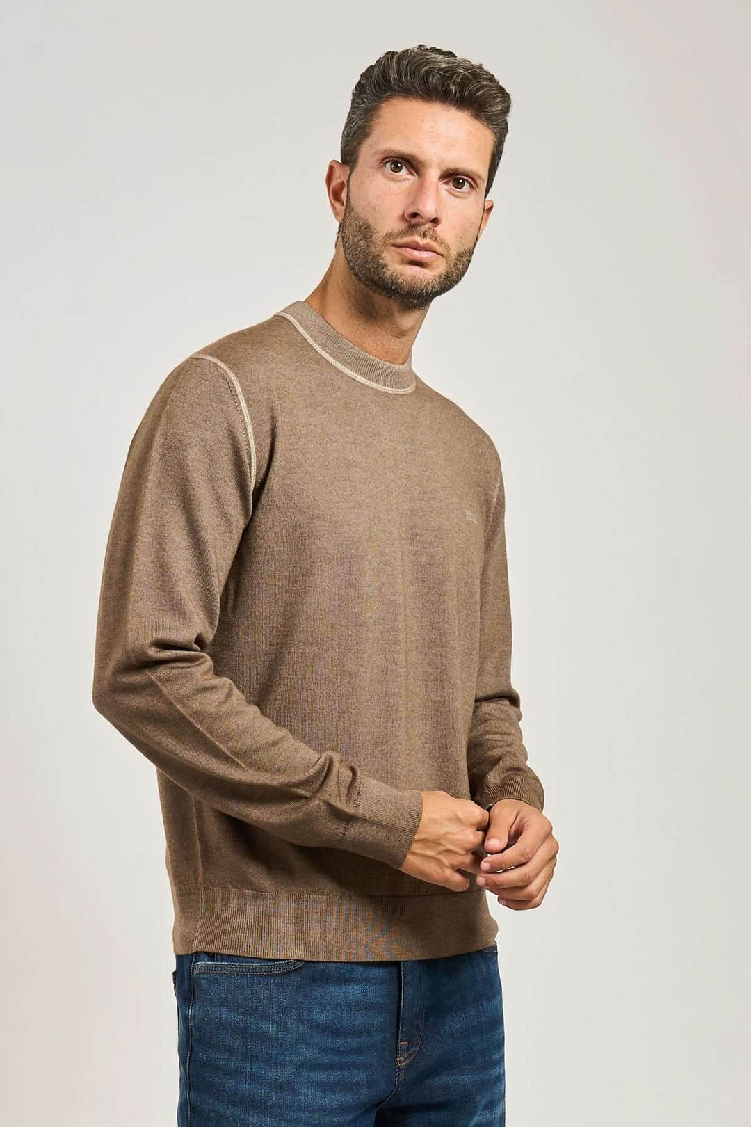 Homme portant un chandail en laine vierge à col rond de la collection BOSS Orange, maille souple et confortable, couleur beige.