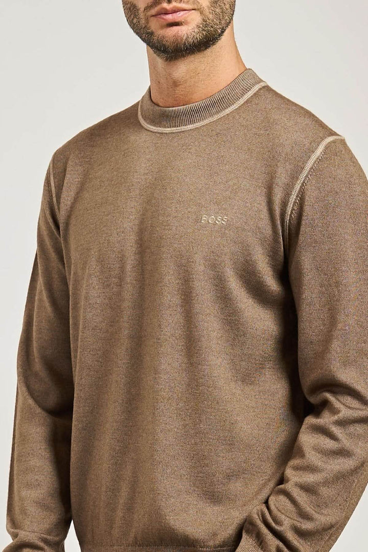 Homme portant un chandail en laine vierge à col rond de la collection BOSS Orange, finition côtelée et logo brodé sur la poitrine.