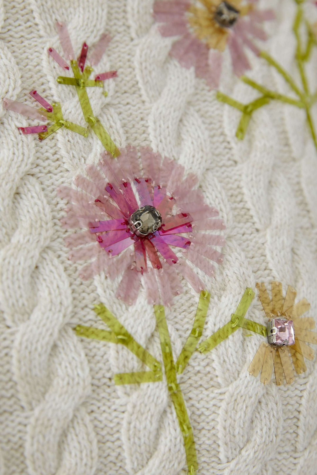 Chandail en maille torsadée avec broderies florales délicates, offrant élégance et douceur. Décris moi le produit en français.