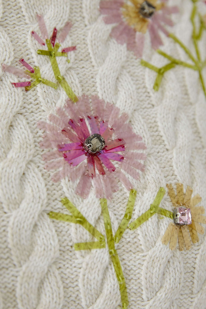 Chandail en maille torsadée avec broderies florales délicates, offrant élégance et douceur. Décris moi le produit en français.