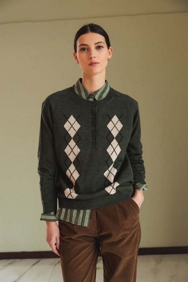 Chandail en mérinos à motif argyle, col rond côtelé, style preppy-chic avec chemise rayée et pantalon marron, look décontracté.
