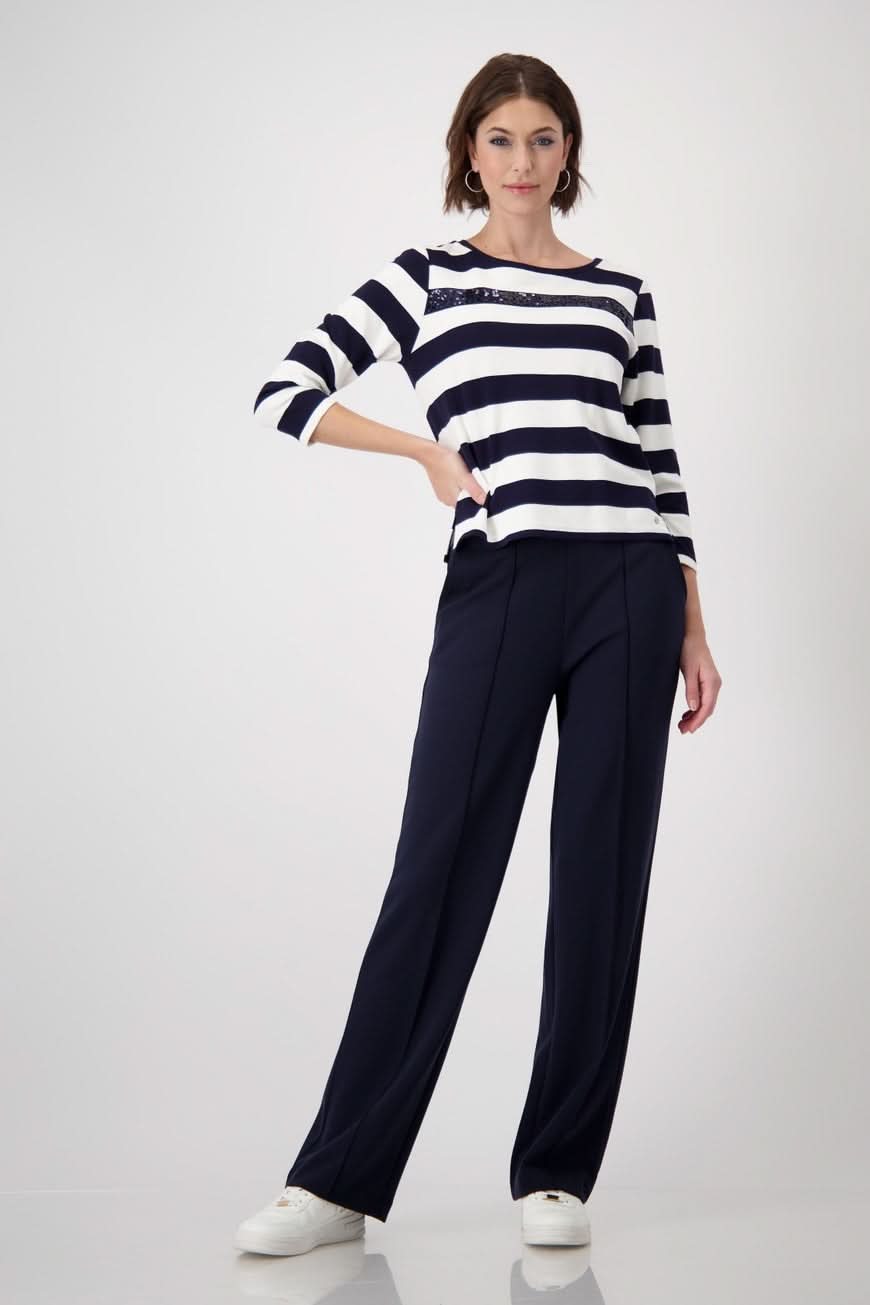 Chandail en tissu sweat rayé avec sequins, porté avec un pantalon élégant, look décontracté et raffiné.