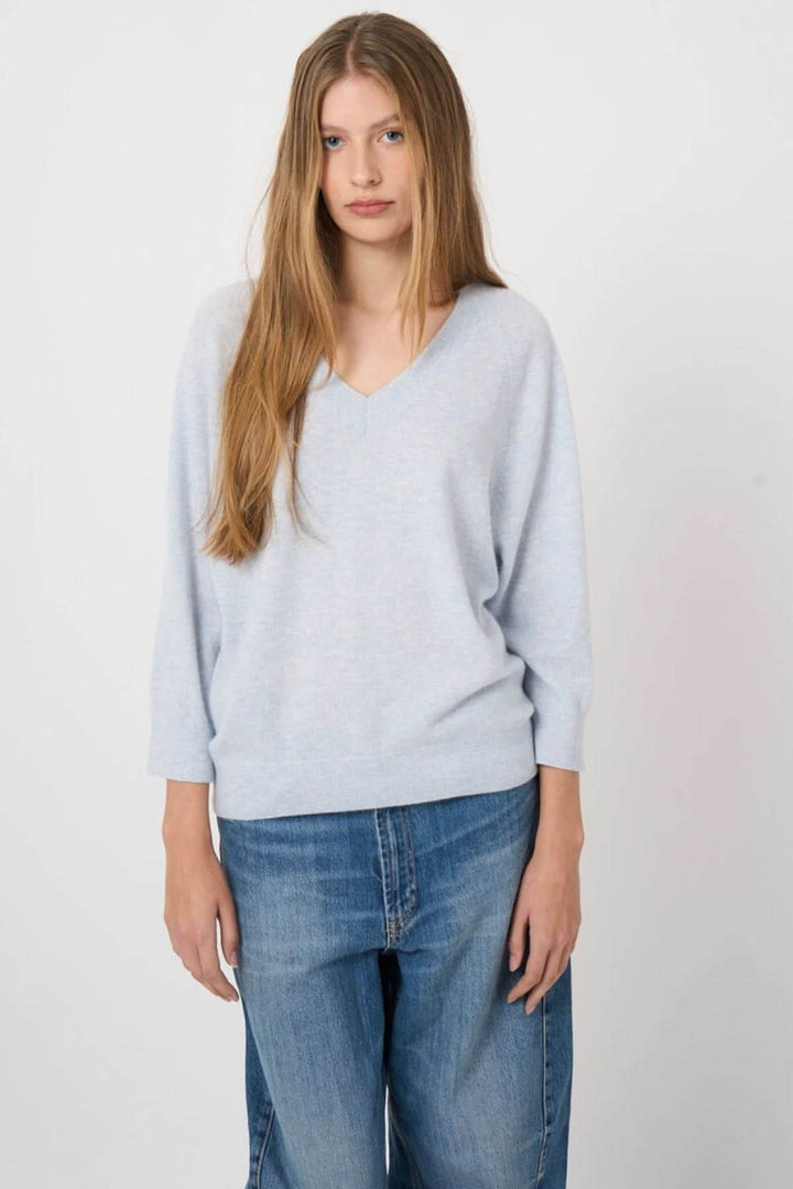 Femme portant un chandail en tricot à col en V, coupe droite et manches longues, style décontracté et classique.