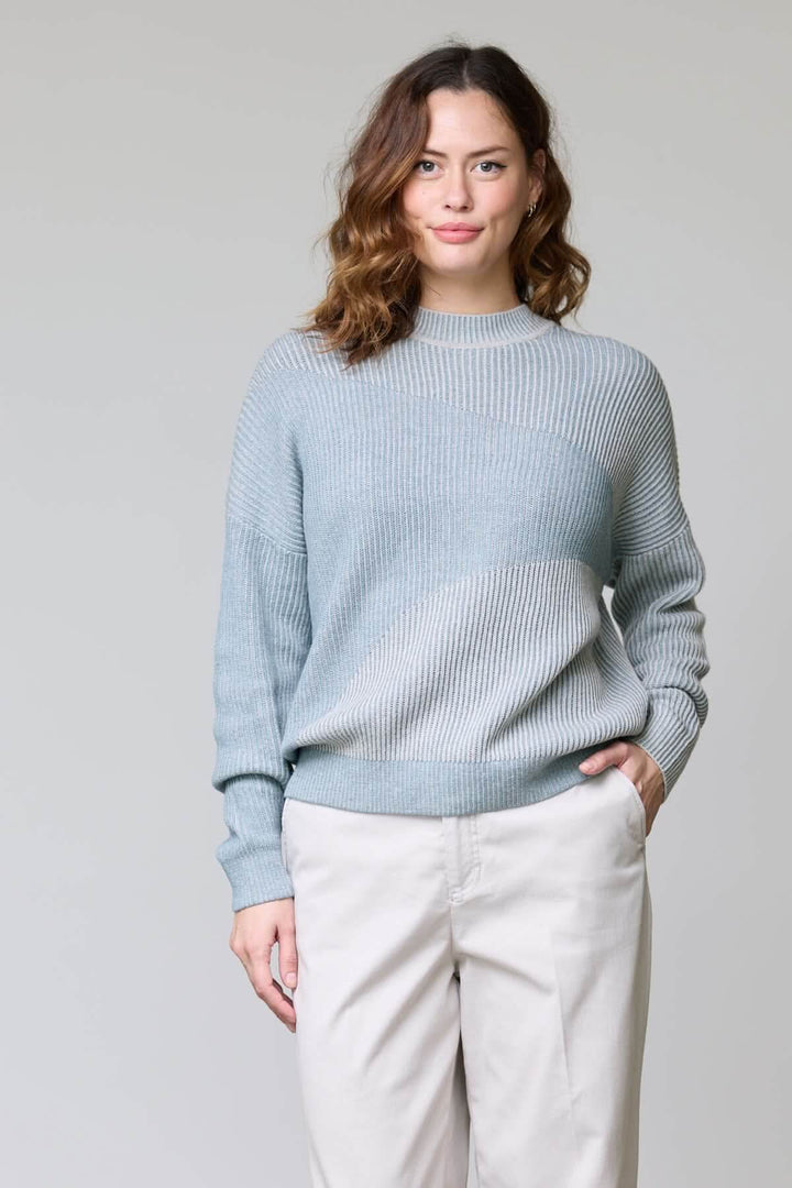 Woman wearing a chandail en tricot côtelé with ribbed texture, round neckline, and relaxed fit, demonstrating a casual, modern style.