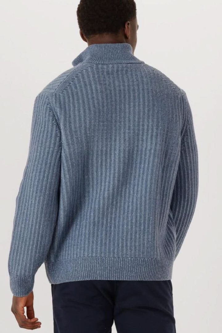 Homme portant un chandail en tricot à demi-glissière bleu, style décontracté soigné et moderne.