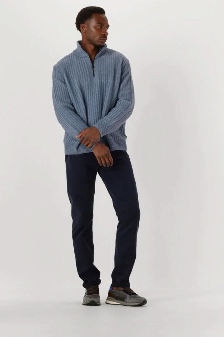 Homme portant un chandail en tricot à demi-glissière bleu avec un col montant moderne, style décontracté et élégant sur fond blanc.