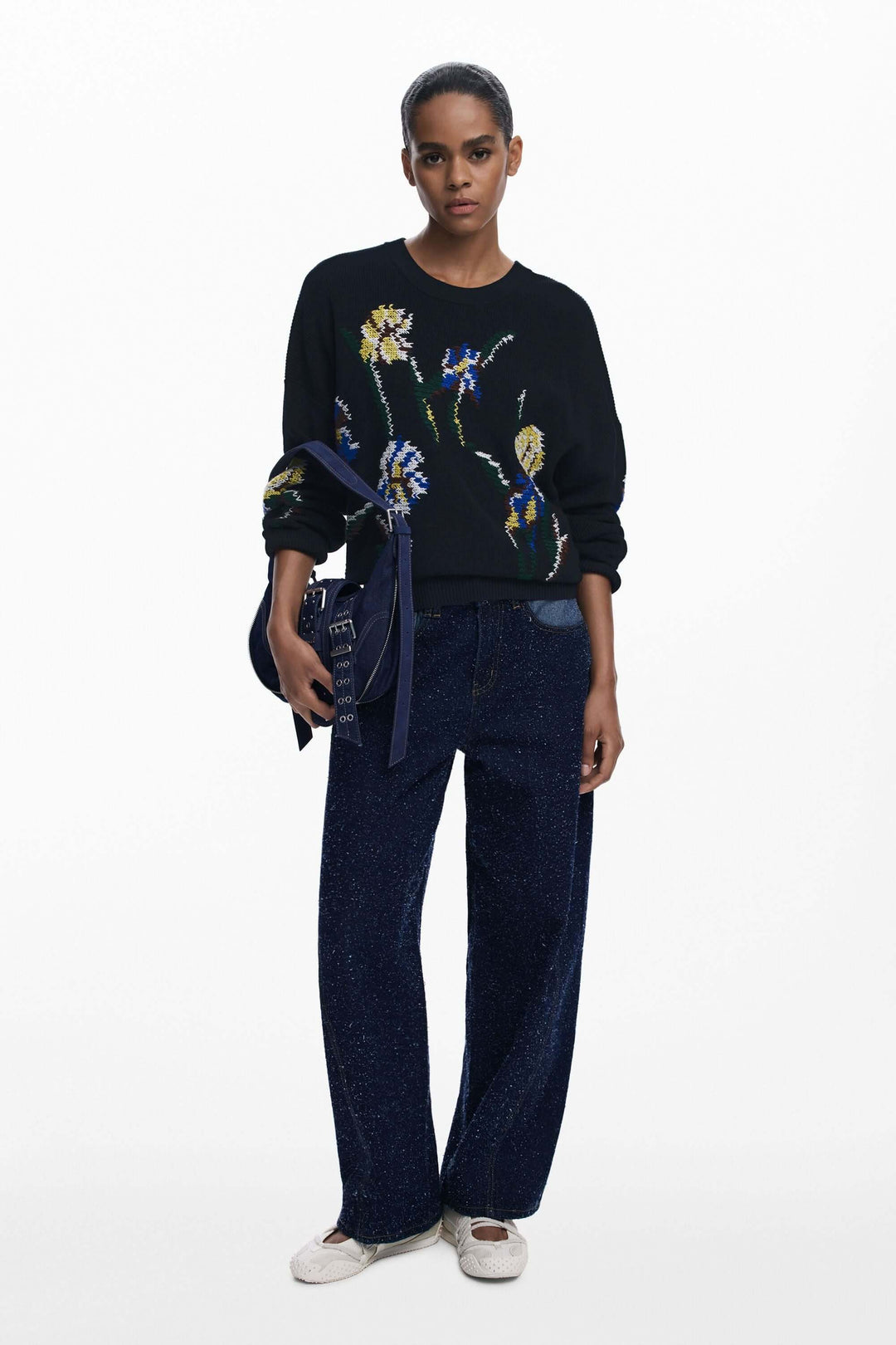 Chandail à fleurs brodées avec motifs floraux colorés, coupe ample et encolure ronde porté par une personne, ensemble élégant et moderne.