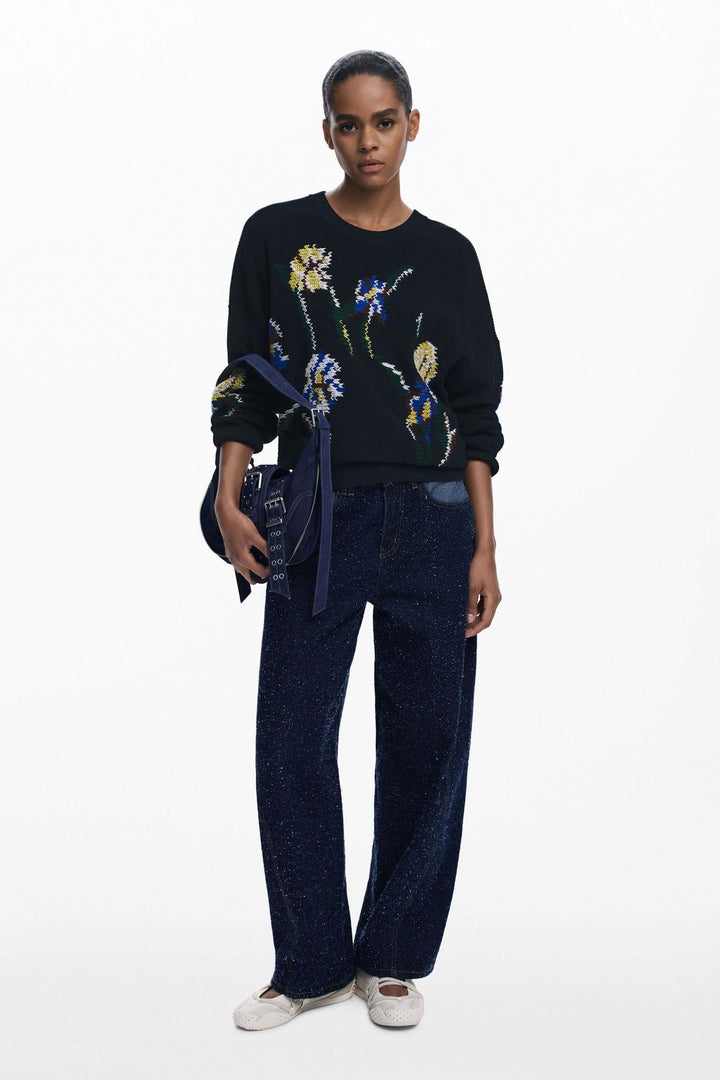 Chandail à fleurs brodées avec motifs floraux colorés, coupe ample et encolure ronde porté par une personne, ensemble élégant et moderne.